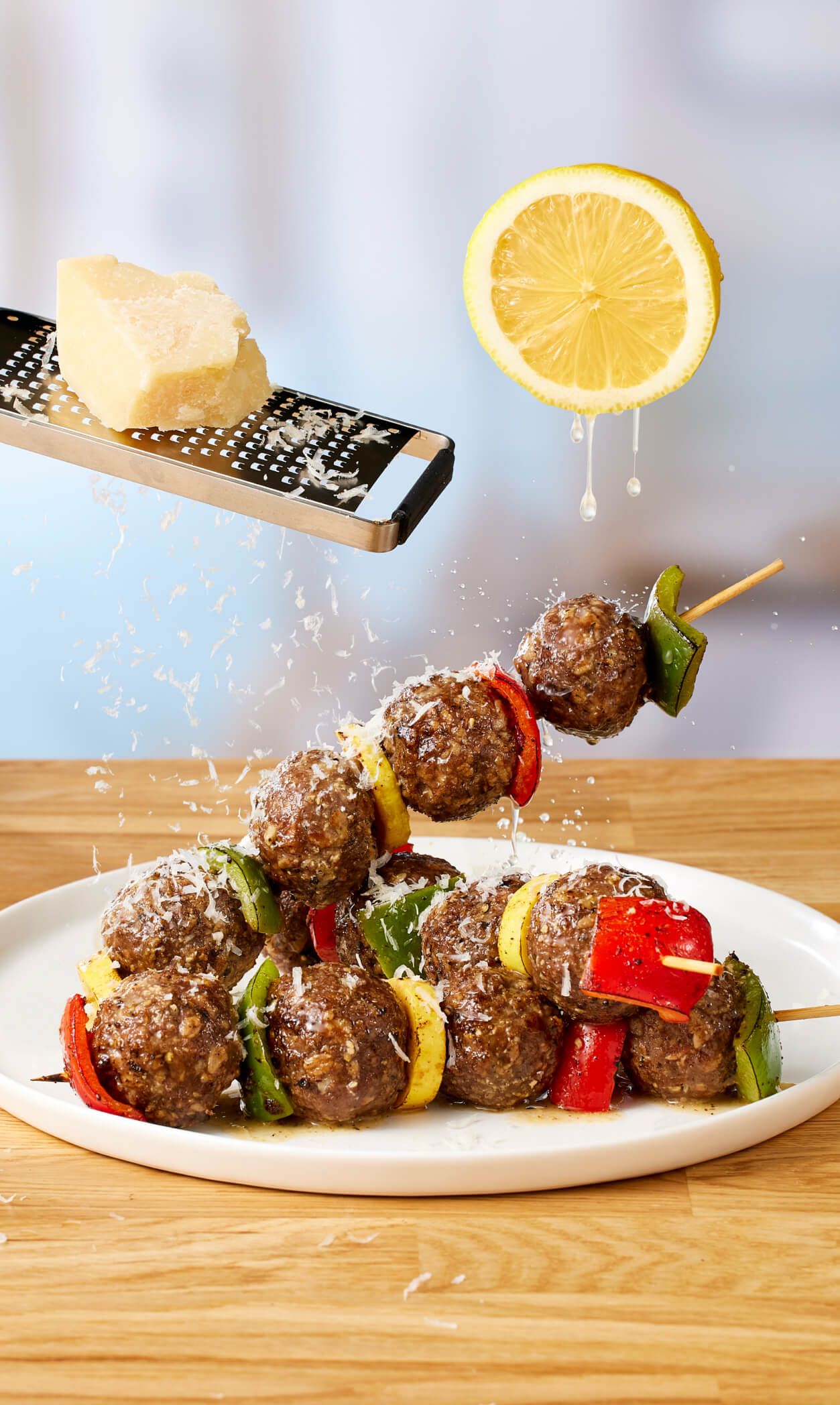 Meatballs and vegetables skewered, with cheese and lemon garnish.
